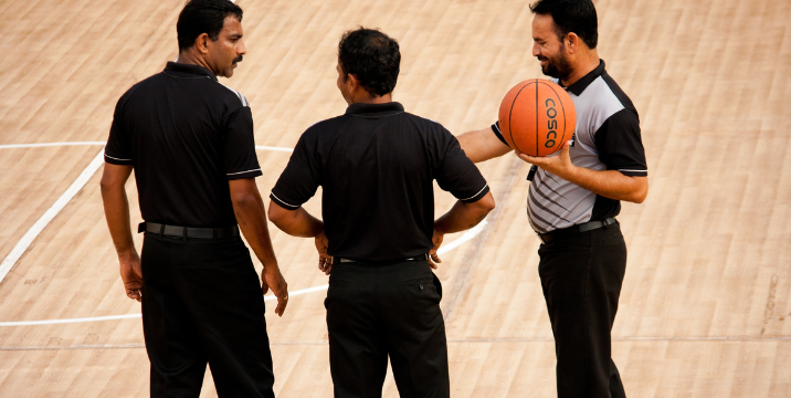 Basketball referees discussing assignments during a game.